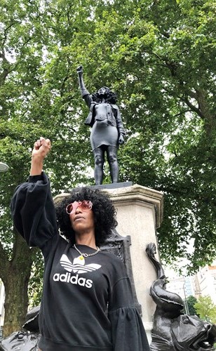 الناشطة المناهضة للعنصرية جين ريد تلتقط صورة أمام تمثالها الذي نصب بدلا من تمثال تاجر العبيد ادوارد كولستون في بريستول (رويترز)