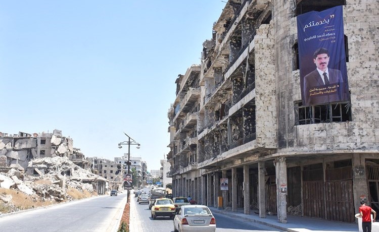 صورة لمرشح لمجلس الشعب على احد الابنية التي دمرتها الحرب في حلب	(أ.ف.پ)