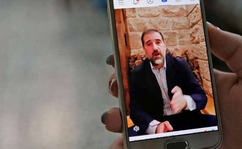 صورة ارشيفية لسيدة تشاهد تسجيلا لرامي مخلوف على الهاتف المحمول