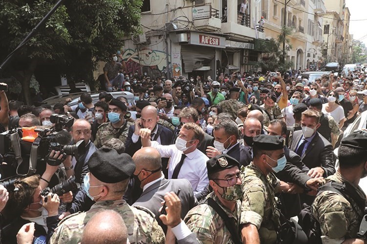 الرئيس الفرنسي إيمانويل ماكرون محييا لبنانيين احتشدوا خلال تفقده حي الجميزة المدمر في بيروت