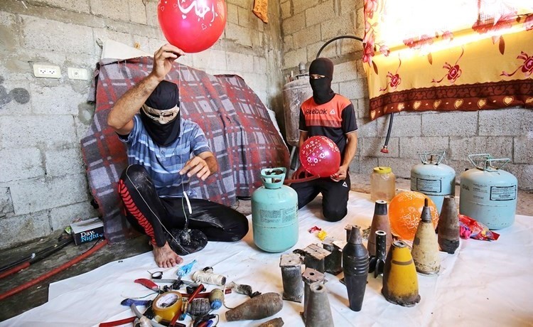 فلسطينيان بمدينة رفع في غزة أمس يعدان البالونات الحارقة التي تستخدمها المقاومة ضد قوات الاحتلال	(ا.ف.ب)