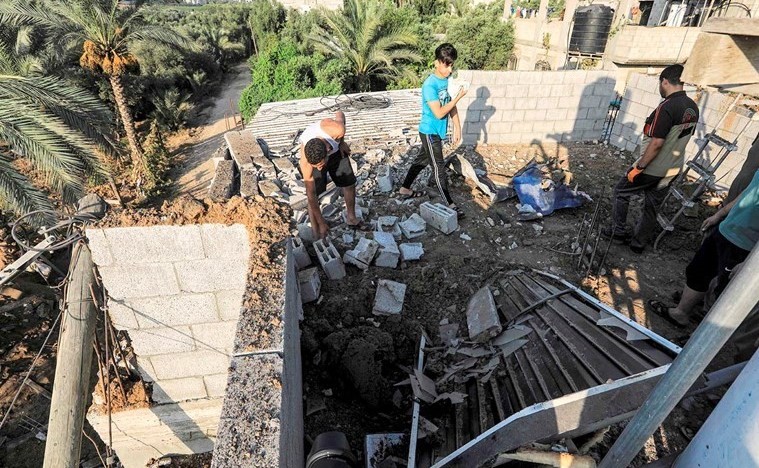 فلسطيونيون يتفقدون الانقاض والحطام على سطح اثر غارة جوية اسرائيلية على قطاع غزة(أ.ف.پ)