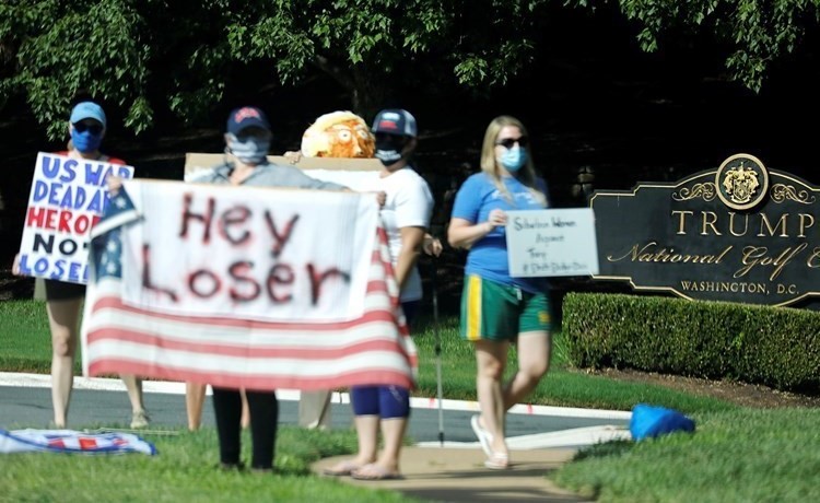 متظاهرون معارضون للرئيس دونالد ترامب يحتجون خلال توجهه للعب الغولف في ناديه الخاص بفيرجينيا	(رويترز)