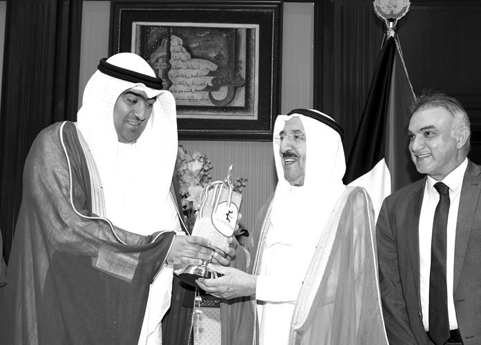 سمو الامير الراحل الشيخ صباح الاحمد يتسلم درعا تذكارية من وزير التجارة والصناعة خالد الروضان ويبدو مدير عام الهيئة العامة للصناعة عبد الكريم تقي بعد شرح مشروع السالمي والشدادية