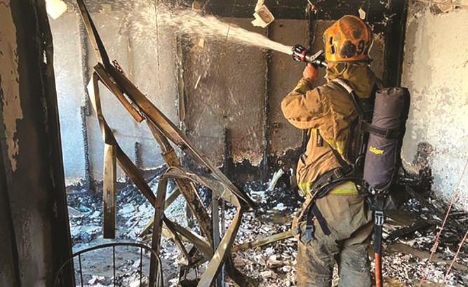 أحد رجال الاطفاء يحكم السيطرة على حريق الشقة