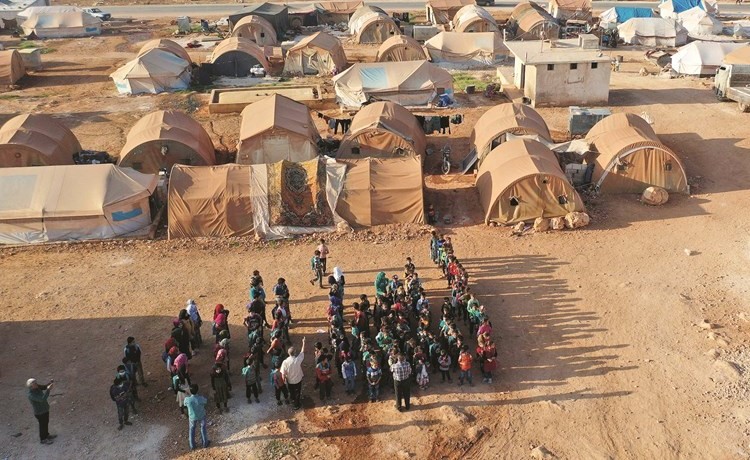 صورة جوية لأطفال سوريين قبل دخولهم احدى الخيم التي تحولت مدرسة في معرة مصرين في ادلب(أ.ف.پ)