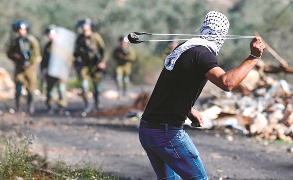 متظاهر فلسطيني يلقي بالحجارة على قوات الاحتلال خلال اشتباكات في الضفة امس الاول	 (ا.ف.پ)