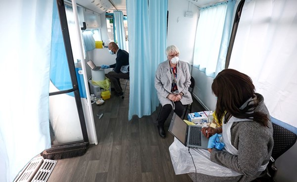 سيدة تتلقى لقاح أسترازينيكا في حافلة حولت إلى مركز تطعيم متنقل في لندن	(رويترز)