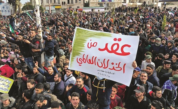 سوريون يرفعون شعار عقد من الخذلان العالمي خلال مظاهرة في ادلب بمناسبة مرور 10 سنوات على الحرب(أ.ف.پ)
