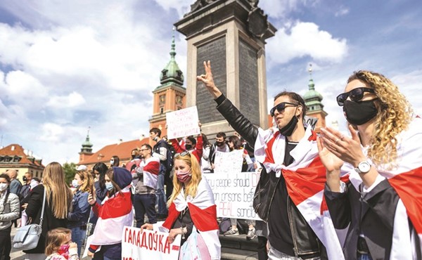 متظاهرون بيلاروسيون يحملون علم المعارضة في احتجاج في وارسو	(أ.ف.پ)