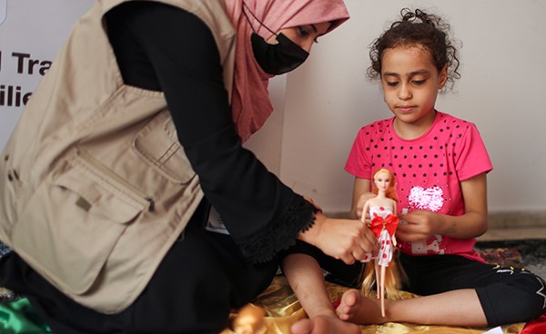 معالجة نفسية تلعب مع الطفلة سوزي اشكنتنا التي انقذت من تحت ركام منزلها بعد استشهاد والدتها واخوتها الاربعة في غارة على غزة (رويترز)