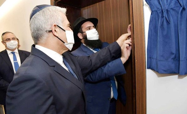 وزير خارجية إسرائيل يائير لابيد يقوم بتقليد لصق الميزوزا على باب السفارة في أبوظبي 	(رويترز)