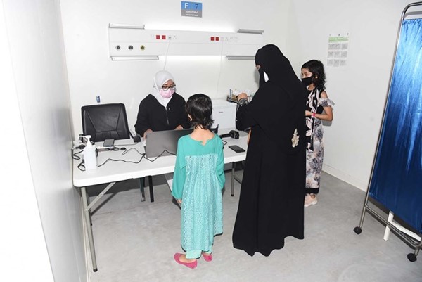 إحدى الأمهات مع طفلتيها في مركز التطعيم (أحمد علي)