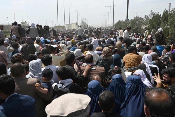 أفغان يتجمعون على جانب طريق بالقرب من الجزء العسكري من مطار كابول على أمل الفرار من البلاد (أ.ف.پ)