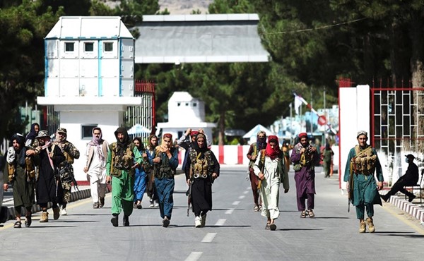 عناصر طالبان يسيرون أمام البوابة الرئيسية لمطار كابول	(أ.ف.پ)