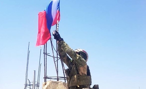 صورة نشرتها مواقع التواصل لجندي يرفع العلم الروسي في درعا بعد اتفاق التسوية 	(انترنت)