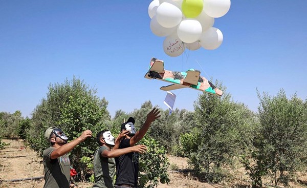 فلسطينيون يطلقون بالونات تحمل مجسم طائرة من غزة باتجاه الأراضي المحتلة (أ.ف.پ)