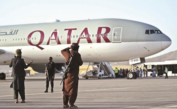 رجل أمن قطري ومقاتلان من طالبان يحرسون المسافرين خلال صعود طائرة قطرية في مطار كابول أمس (أ.ف.پ)