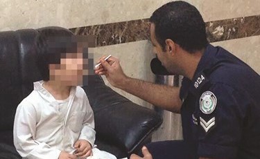 أحد رجال الأمن يطعم طفلا تم العثور عليه