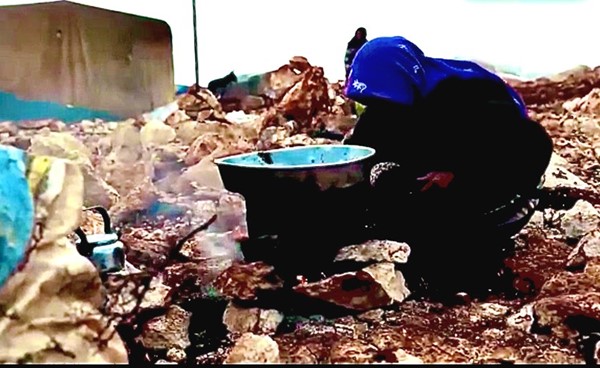 لاجئة سورية تطبخ على الاخشاب في العراء