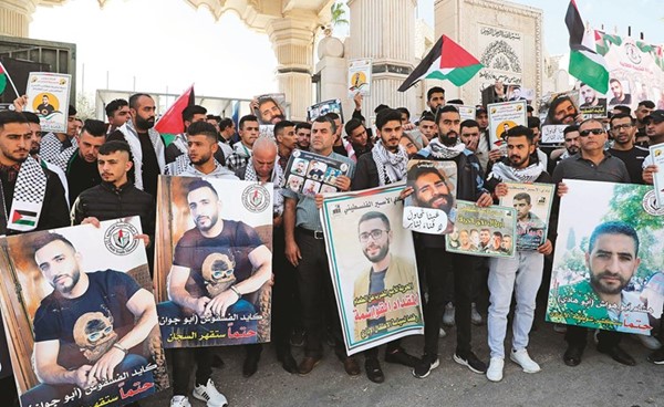 فلسطينيون يرفعون صورا لأسرى مضربين عن الطعام في سجون الاحتلال خلال مسيرة داعمة لهم في مدينة الخليل امس	(أ.ف.پ)
