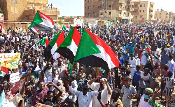 سودانيون يلوحون بعلم بلدهم ويرفعون لافتات ضد «الانقلاب» خلال تظاهرات في أم درمان أمس (ا.ف.پ)