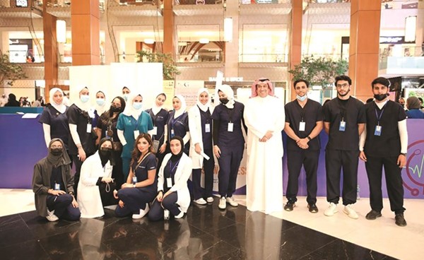 نائب رئيس مجلس الأمة أحمد الشحومي متوسطا طلبة وطالبات الكلية خلال المعرض