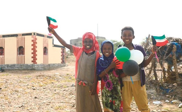 أطفال يرفعون أعلام الكويت بعد الاستفادة من المبادرة