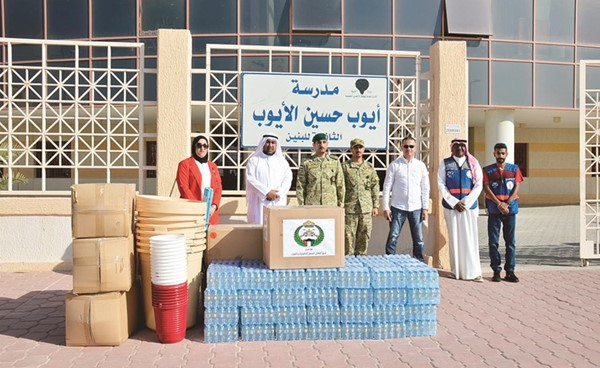 مسؤولو محافظة الأحمدي والحرس الوطني خلال تسليم المستلزمات إلى المدرسة