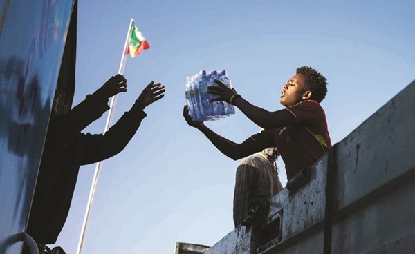 احد المتطوعين يناول زجاجات مياه للقوات الإثيوبية التي تواجه متمردي تيغراي في أديس ابابا	(أ.ف.پ)