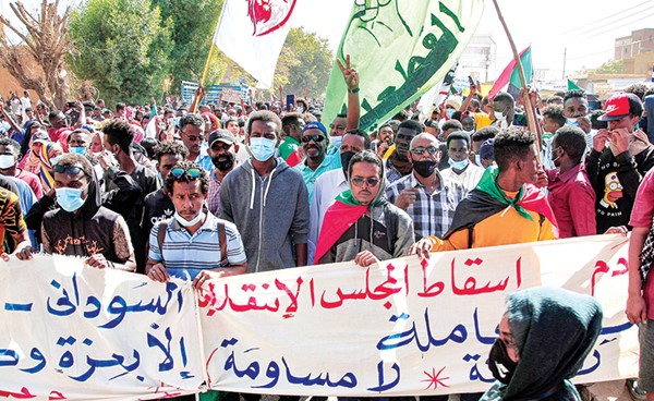 محتجون يرفعون لافتات مناهضة للحكم العسكري خلال تظاهرة حاشدة بالخرطوم أمس (أ.ف.پ)