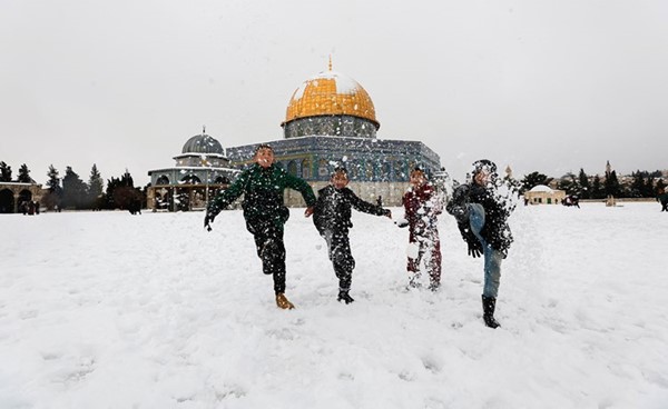 أطفال يلهون بالثلوج المتساقطة في ساحة المسجد الأقصى 	(أ.ف.پ)