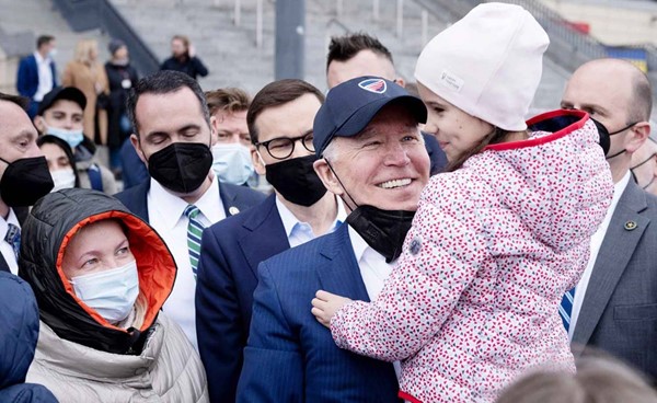 الرئيس الأميركي جو بايدن حاملاً طفلة خلال لقائه لاجئين أوكرانيين في پولندا أمس (ا.ف.پ)