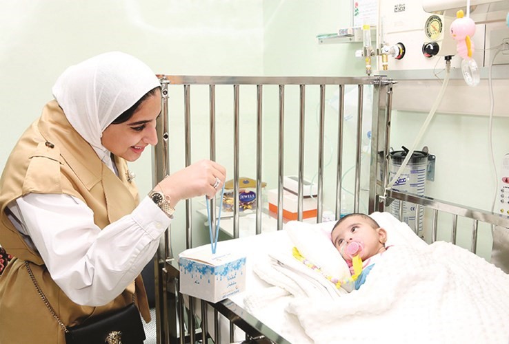 فجر الكندري من فريق المسؤولية المجتمعية تقدم القرقيعان لأحد الأطفال المرضى