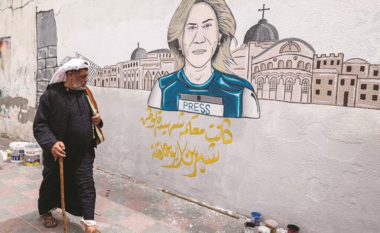 فلسطيني يمر إلى جوار رسم جداري في خان يونس بغزة يؤبن الصحافية الفلسطينية شيرين أبو عاقلة	(ا.ف.پ)