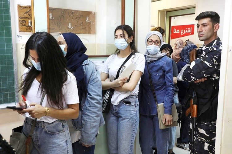 لبنانيات يقفن في طابور داخل أحد مراكز الاقتراع في بيروت بحراسة أمنية	(رويترز)