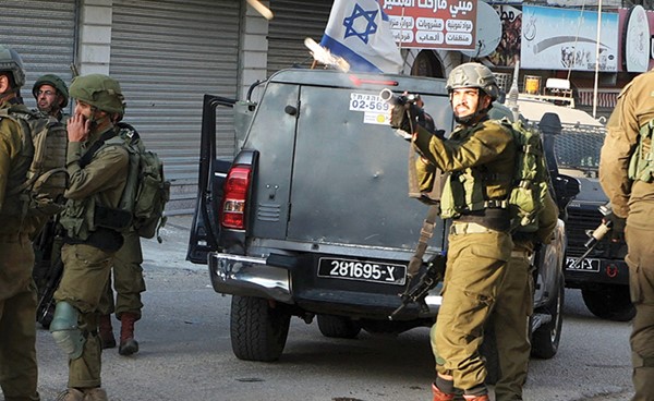 جندي إسرائيلي يطلق الغاز المسيل للدموع على فلسطينيين خلال احتجاجات في الضفة الغربية (أ.ف.پ)