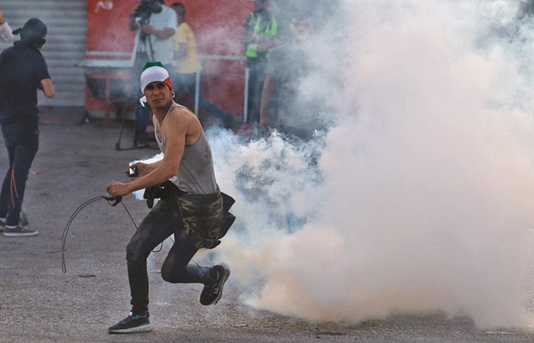 فلسطيني يرد عبوة غاز مسيل للدموع اطلقتها قوات الاحتلال في رام الله(أ.ف.پ)