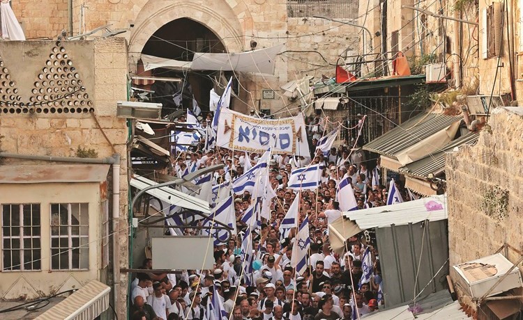مستوطنون يقتحمون القدس القديمة خلال مسيرة الأعلام وفي الإطار فلسطيني يرد عبوة غاز مسيل للدموع أطلقتها قوات الاحتلال في رام الله	(أ.ف.پ)