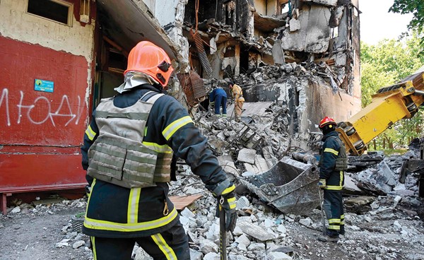  عمال الإنقاذ يفككون أنقاض مبنى سكني دمر جزئيا بسبب القصف الروسي في خاركيف (أ.ف.پ)