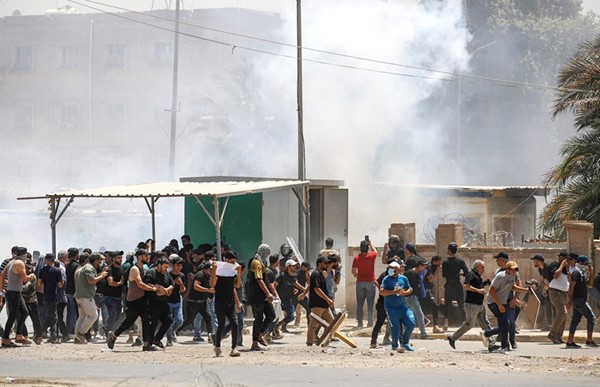 متظاهرون يفرون من قنابل الغاز المسيل للدموع عند إحدى بوابات المنطقة الخضراء قبل اقتحامها أمس(أ.ف.پ)