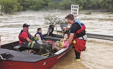 فريق إنقاذ لدى إخلاء سكان من منازلهم بقارب	(رويترز)