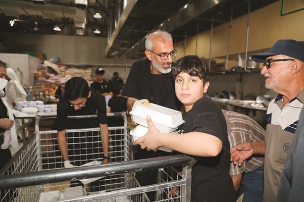عدد من المتطوعين خلال إعداد الوجبات للتوزيع في الحسينية الكربلائية