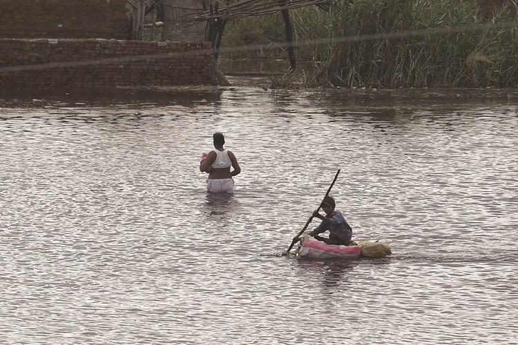 رجل وطفل باكستانيان يتنقلان وسط مياه الفيضان 	(أ.ف.پ)
