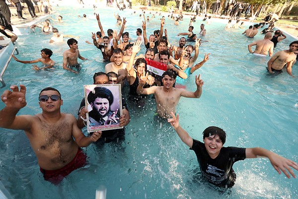  أنصار الصدر يحملون صورته ويسبحون في مسبح القصر الرئاسي في المنطقة الخضراء ببغداد (رويترز)