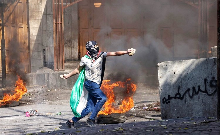 شاب فلسطيني يلقي بالحجارة في اتجاه قوات الاحتلال خلال مواجهات في مدينة الخليل بالضفة الغربية المحتلة (أ.ف.پ)