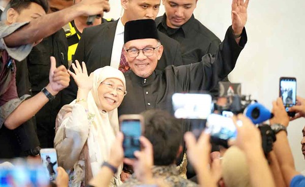 رئيس الوزراء الماليزي الجديد أنور إبراهيم وزوجته عقب أدائه اليمين الدستورية أمس (رويترز)