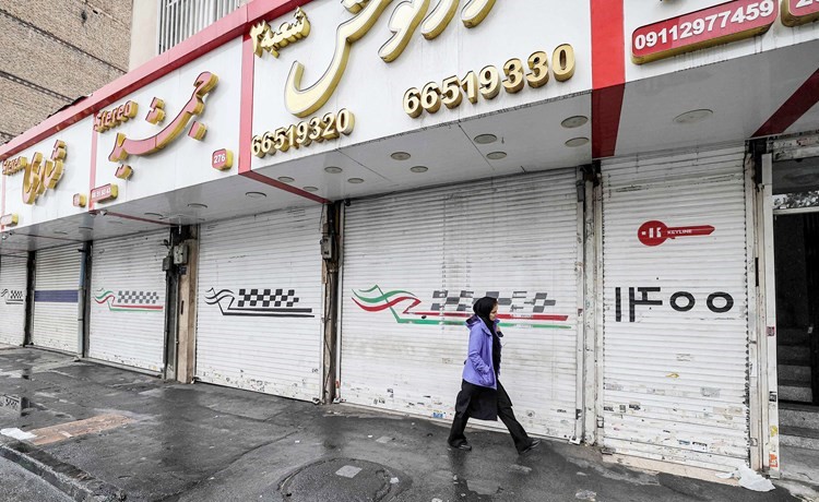 إيرانية تسير بجوار متاجر مغلقة وسط طهران أمس تضامنا مع الاحتجاجات	(أ.ف.پ)
