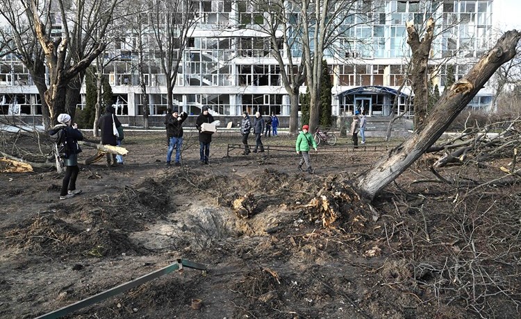 أوكرانيون بجوار حفرة عند مبنى تعليمي في كييڤ تضرر جراء هجوم صاروخي روسي	(أ.ف.پ)