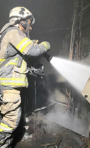 رجل اطفاء يخمد النيران بتسليط الماء على مصدر اللهب